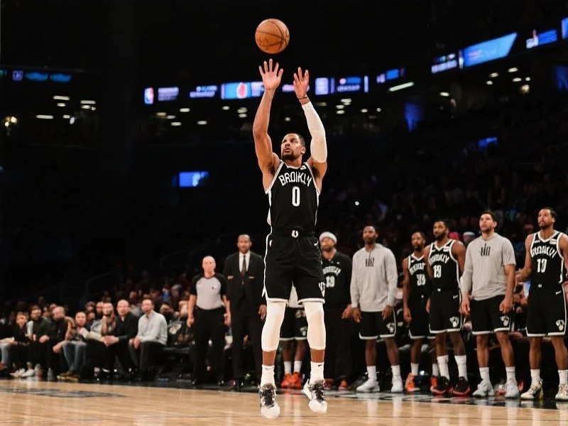 一位NBA明星球员在季后赛关键时刻投篮，面部表情专注，身后队友和对手紧张观战，赛场灯光聚焦球员